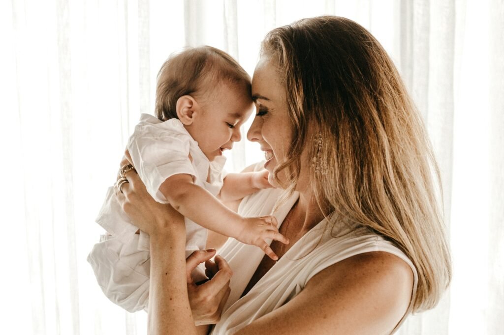Mother lifting her baby in soft morning light
